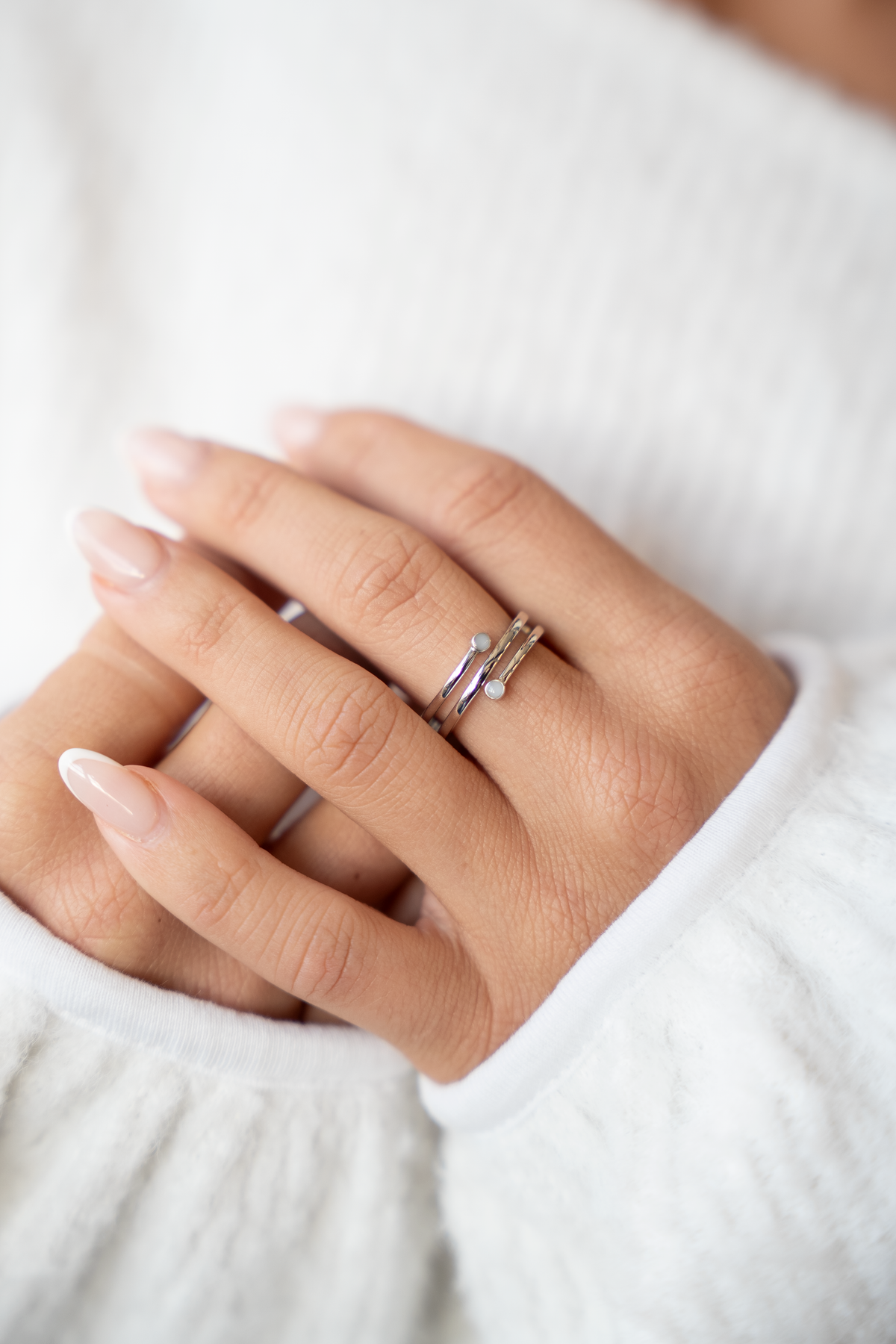 Nahaufnahme gefalteter Hände, am Ringfinger der silberne Aurore Spiralring mit zwei runden Muttermilchsteinchen
