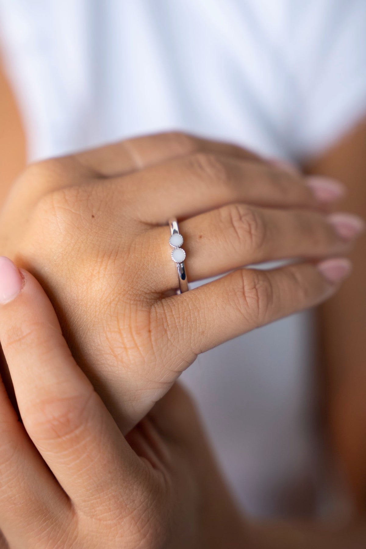 Silberner Bo-Ring mit zwei kleinen Muttermilchsteinen nebeneinander, am Ringfinger getragen.