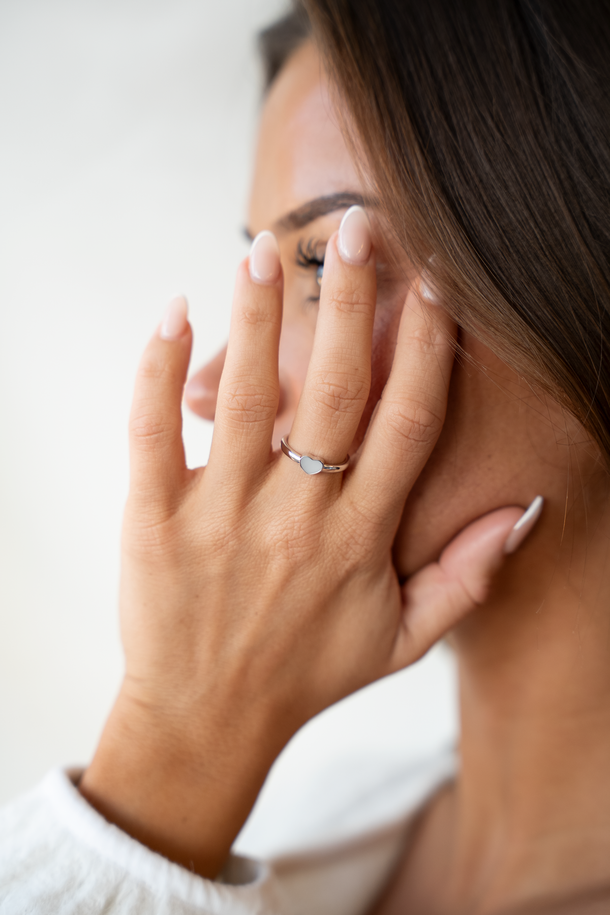 Hand an Wange und Auge, am Ringfinger der Muttermilchring Lisa mit herzförmigem Stein
