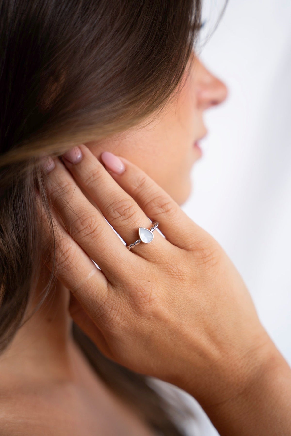 Hand am Ohr mit dem Turning-Droplet-Muttermilchring aus 925er Silber.